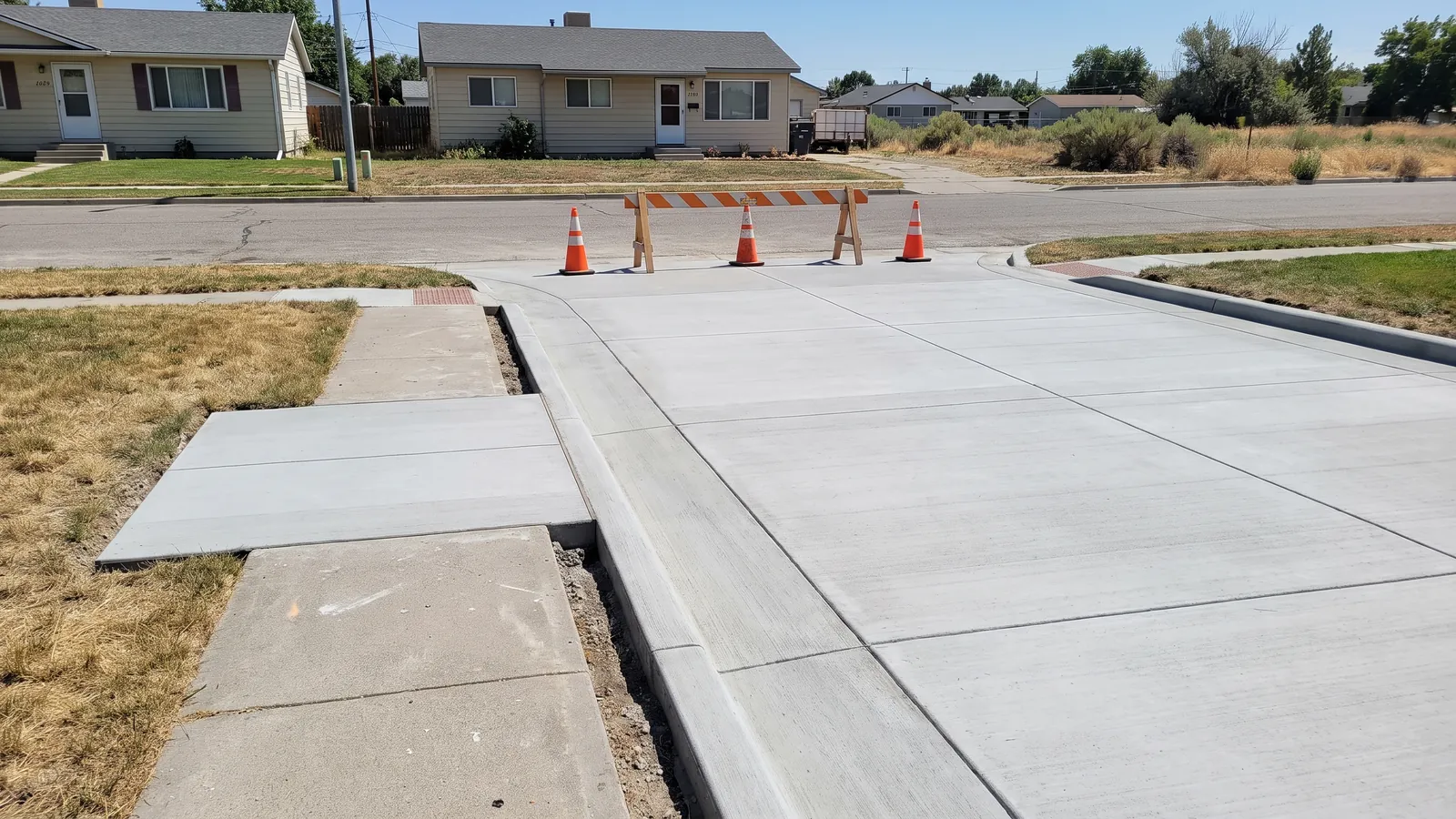 New concrete driveway approach and a replaced detached sidewalk panel beside a landscape strip on an Ada County residential street, forms still in place